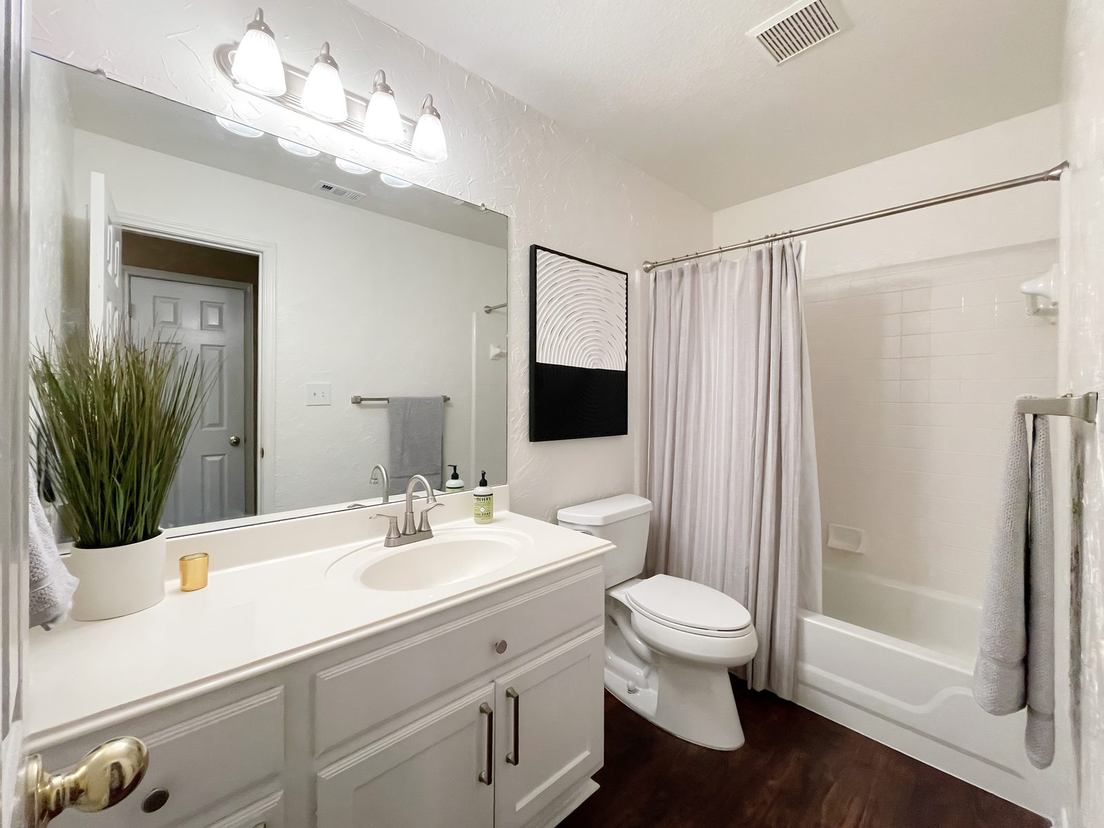 The same bathroom after, white walls with simple black and white art